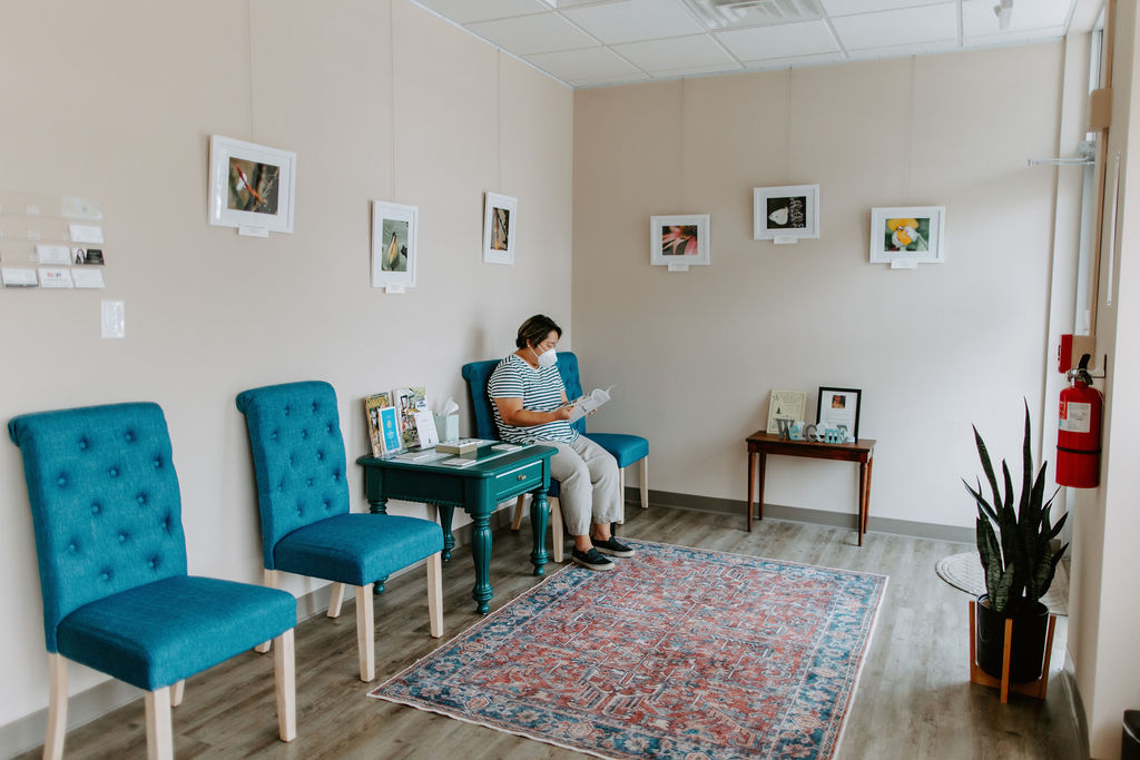 a woman wearing a face mask sitting in the waiting room of Annapolis Family Acupuncture reading a magazine